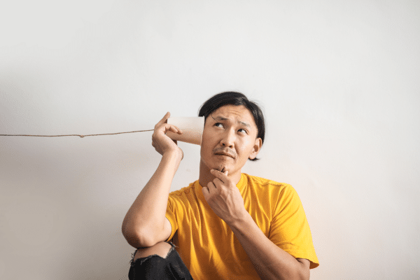 man listening to sounds through string and cup