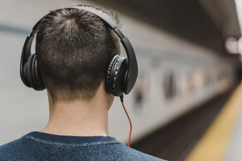 Man listening on headphones near a subway train