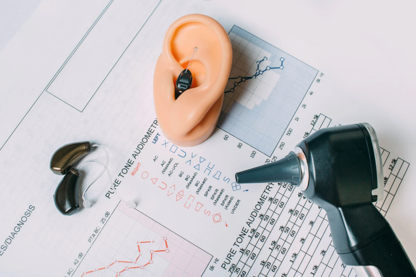 Various items related to hearing tests including documentation, otoscope, hearing aids and a model ear