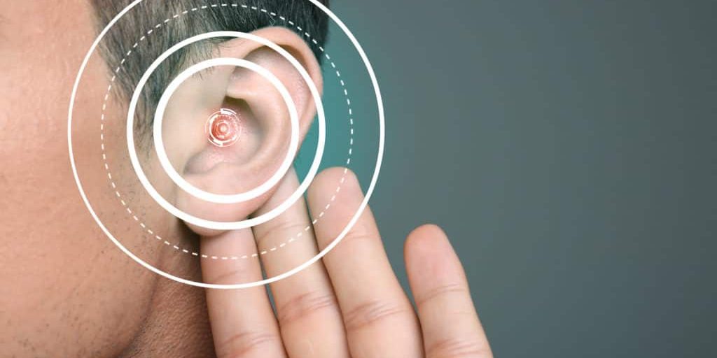 Young man with symptom of hearing loss on color background